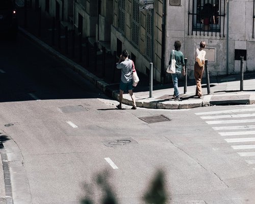 Person walking confidently on a shaded urban sidewalk